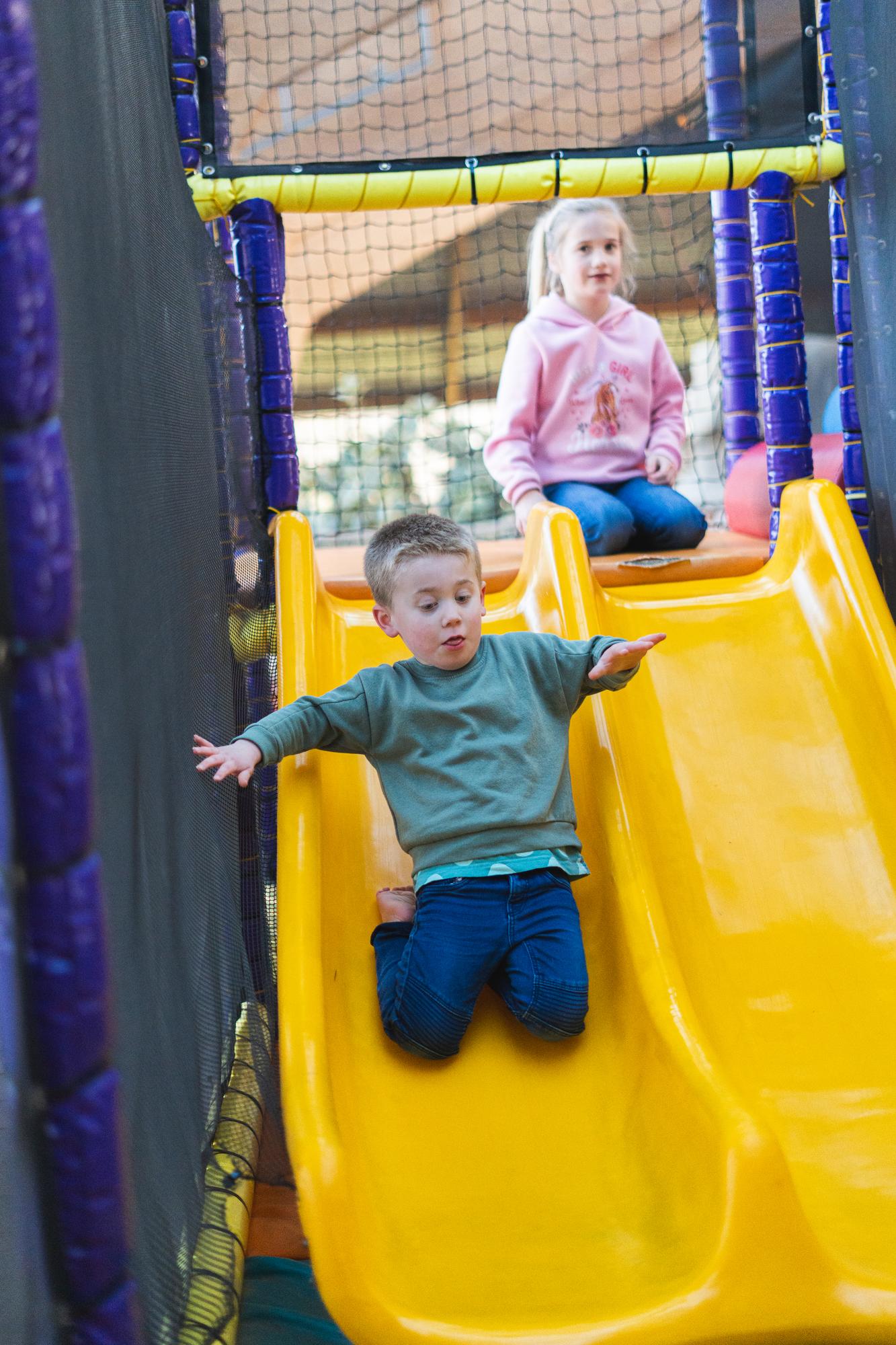 Spelende kinderen gaan van de glijbaan in speelparadijs schateiland zeumeren